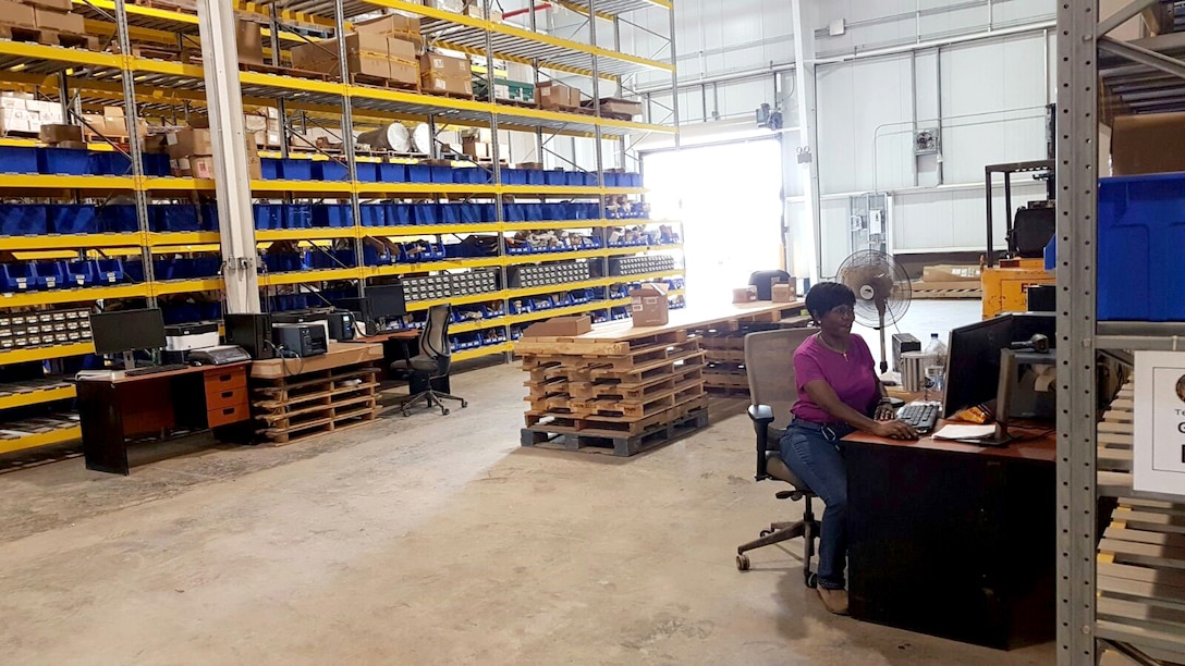 Sheila Gentry, a contracted inventory specialist at DLA Distribution Camp Lemonnier, Djibouti, prepares inventory (background) to be shipped to customers at various sites in the region shortly after the Sept. 30, 2016, opening of the facility.
