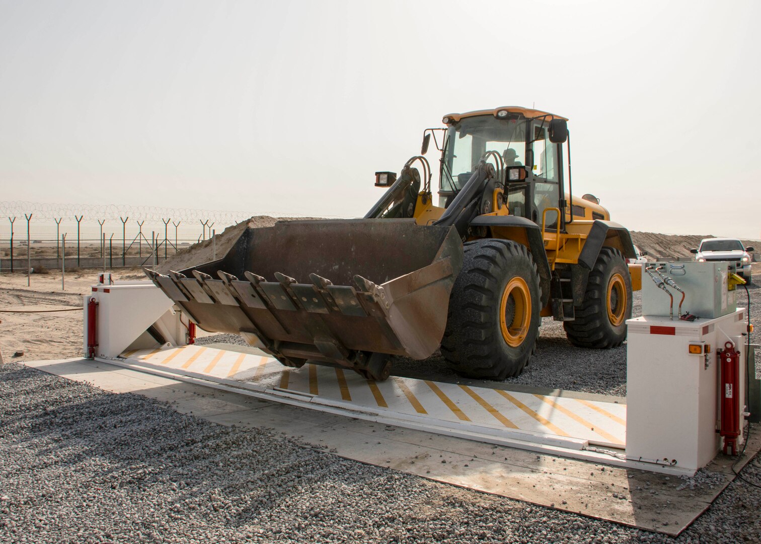 Staff Sgt. Phillip Smith of the 557th RED HORSE drives a front-end loader over a barricade at the new entry control point at an undisclosed location in Southwest Asia Dec. 30, 2016. RED HORSE assisted the 387th Expeditionary Support Squadron civil engineering flight with portions of the road project requiring heavy equipment. (U.S. Air Force photo/Senior Airman Andrew Park)