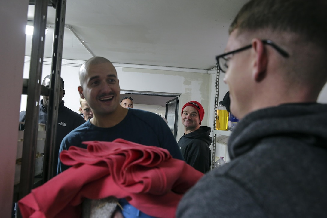 Marine Corps Sgt. Raimundo Jimenez takes blankets from Marine Corps Cpl. Timothy Dykes at a soup kitchen in Catania, Italy, Dec. 29, 2016. Marine Corps photo by Cpl. Alexander Mitchell