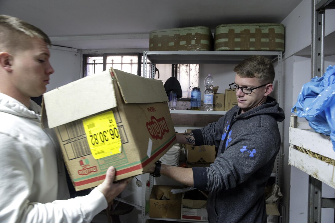 Marine Corps Cpl. Timothy Dykes, right, passes a box to Cpl. Ryan Fratto at a soup kitchen in Catania, Italy, Dec. 29, 2016. Marines and sailors volunteered to clean the facility and serve food during the holiday season. The Marines and sailors are assigned to Special Purpose Marine Air-Ground Task Force Crisis Response Africa Command, which supports operations, contingencies and security cooperation in the U.S. Africa Command area of responsibility. Marine Corps photo by Cpl. Alexander Mitchell
