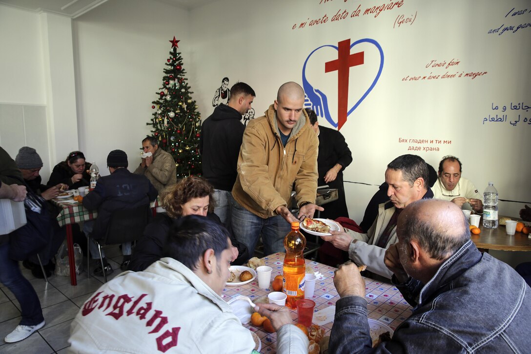 Marine Corps Sgt. Raimundo Jimenez passes a plate of food at a soup kitchen in Catania, Italy, Dec. 29, 2016. Jimenez is a water purification specialist assigned to Special Purpose Marine Air-Ground Task Force Crisis Response Africa, Marine Corps photo by Cpl. Alexander Mitchell