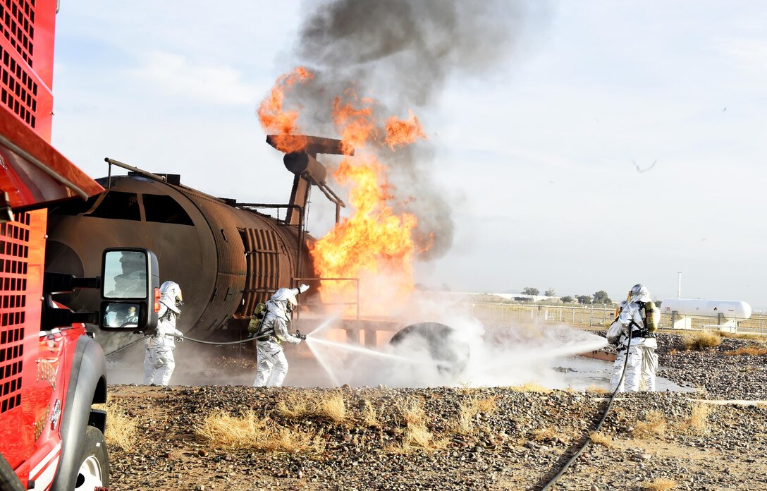 Firefighters with the 56th Civil Engineer Squadron and Gila Bend Fire Department work together using fire hoses during training Dec. 7, 2016, at Luke Air Force Base, Ariz. The firefighters were training on responding to an aircraft fire and use of rapid intervention vehicles. (U.S. Air Force photo by Senior Airman James Hensley)