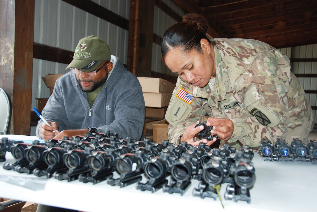Shannon Woodyard from DLA Distribution New Cumberland, Pennsylvania, helps a 10th Mountain Division supply sergeant turn in excess optical sighting devices at Fort Drum, New York.