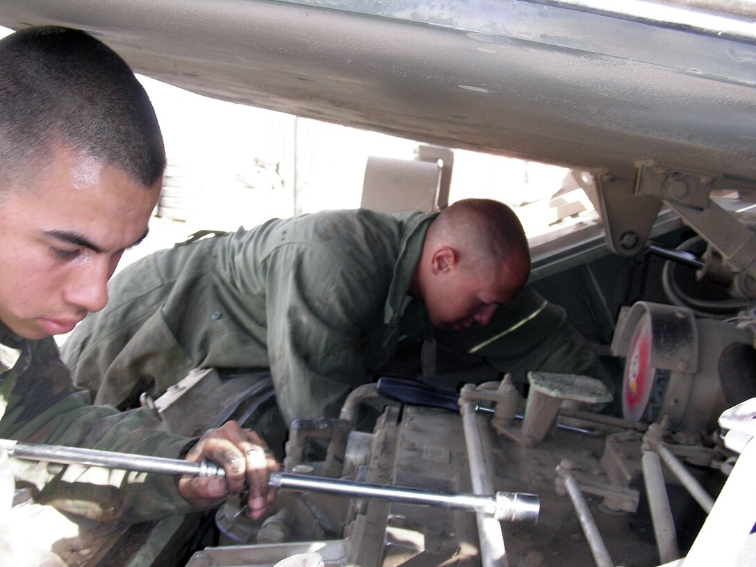 Army Pfc. Guillermo Armendariz and Pfc. James Vail change an engine in a Bradley fighting vehicle in Hit, Iraq. The transmission of the Bradley is a critical part the DLA Warstopper Program makes sure is available.
