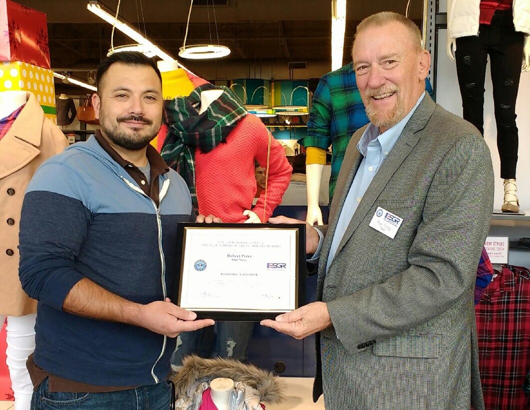 Ray Forgy, Employer Support for the Guard and Reserve volunteer, presents Robert Perez, Old Navy supervisor,  with the Patriot Award Dec. 19, 2016. Tech. Sgt. Shamilta Brock, 433rd Force Support Squadron force management, nominated Mr. Perez for his ability to change work schedules to support annual tour and military drill requirements.  (U.S. Air Force photo by Benjamin Faske)