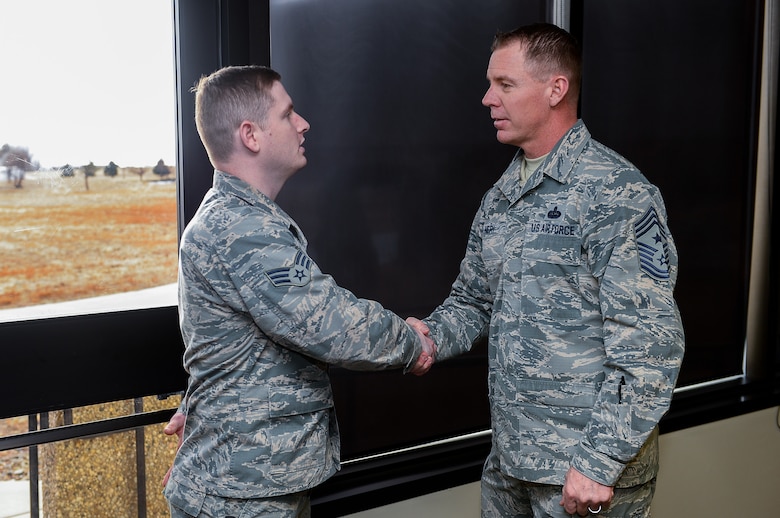Chief Master Sgt. Craig Neri, 14th Air Force Command Chief Master Sergeant, coins Senior Airman Andrade Azevedo, 50th Space Communications Squadron, following a luncheon with Airmen in the Satellite Dish dining facility at Schriever Air Force Base, Colorado, Tuesday, Jan. 3, 2017. Neri recognized Azevedo for his input and investment during the discussion. (U.S. Air Force photo/Christopher DeWitt)