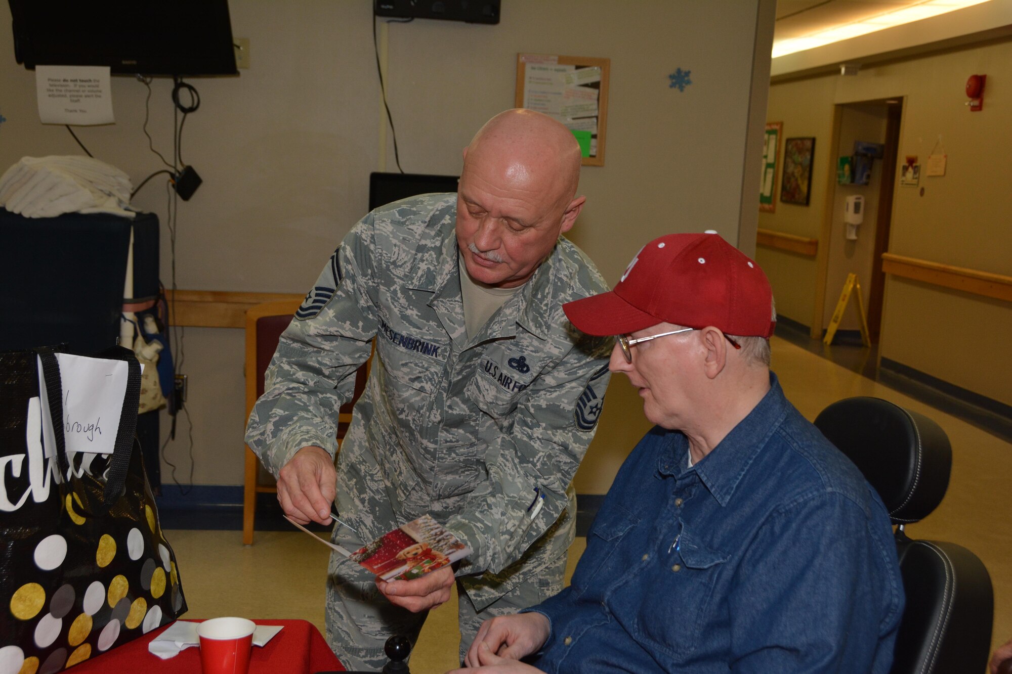 Senior Master Sgt. Rodney Mesenbrink of the 507th Maintenance Squadron presents a gift card to a resident of the Norman Veterans Center Dec. 22, 2016 in Norman, Okla.  Approximately 35 Airmen from Tinker Air Force Base visited and delivered gifts to the Veterans.(U.S. Air Force photo/Maj. Jon Quinlan) 