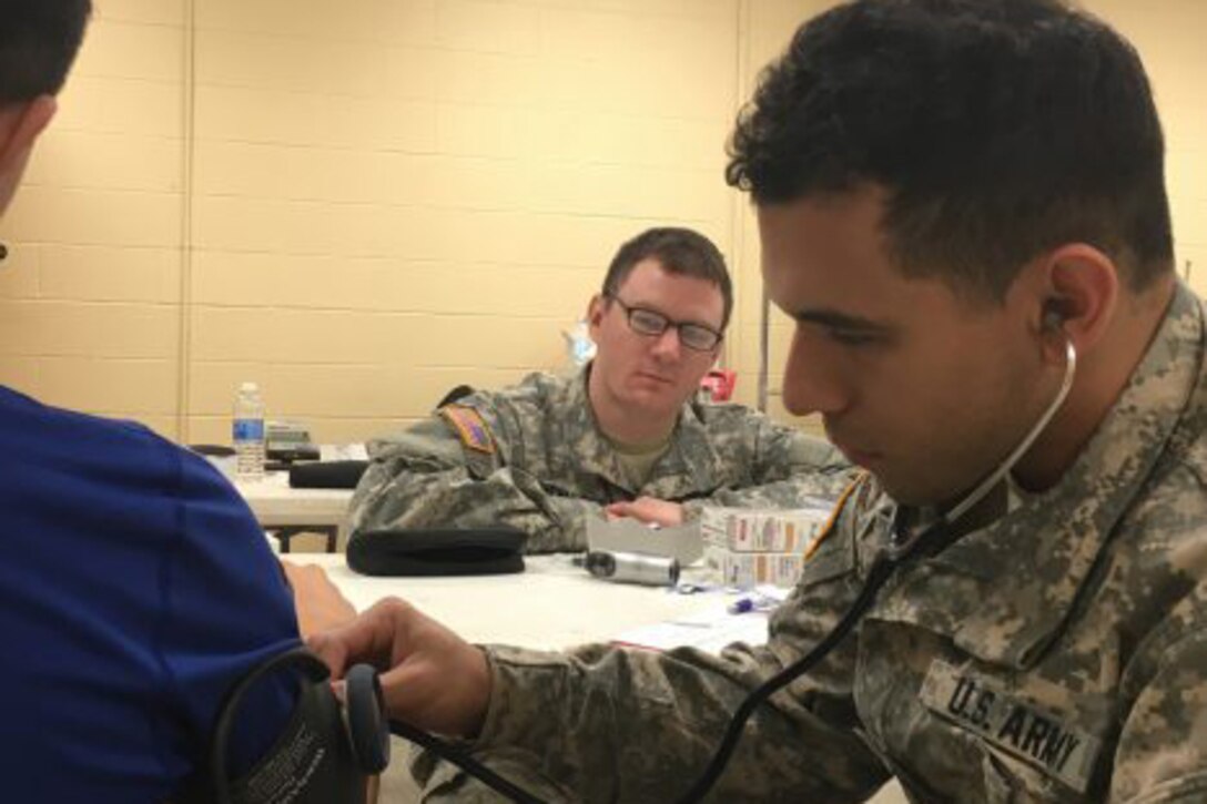 Army Reserve Pfc. Stephen Young, right, checks vitals on a patient as Sgt. Kyle Puchalsky, center, observes during Operation Lone Star at Vela Middle School in Brownsville, Texas, July 25, 2016.  Army photo by Staff Sgt. Syreeta Shaw