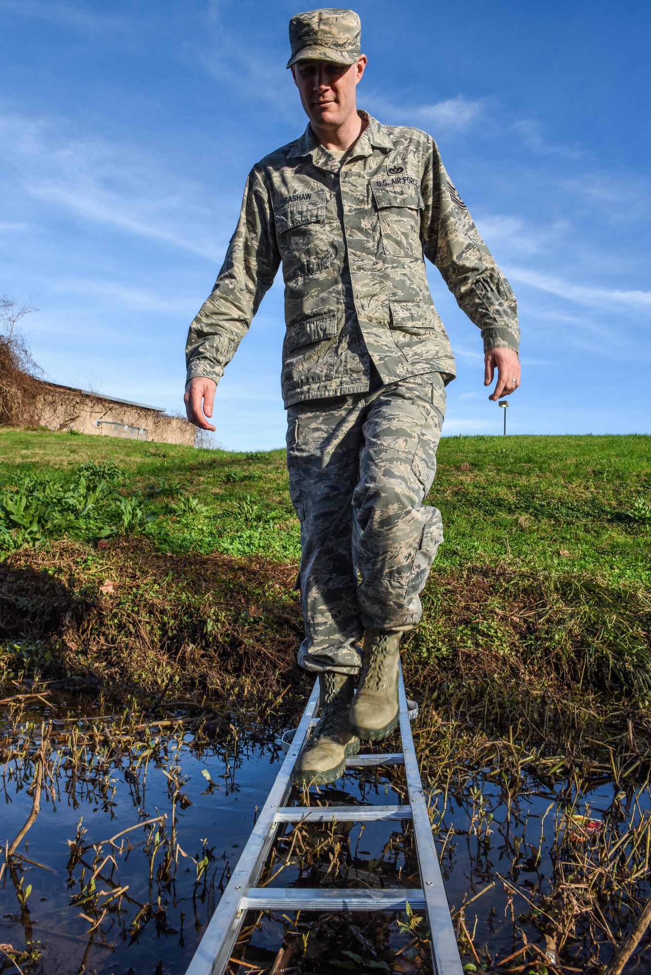 Tech. Sgt. Mark Bashaw, 2nd Civil Engineer Squadron pest management NCO in-charge, carefully crosses a creek at Barksdale Air Force Base, La., Jan. 3, 2017. Pest Management Airman are often called into all areas of the base to remove animals and insects that would pose a danger to base personnel or the Barksdale mission. (U.S. Air force photo/Senior Airman Luke Hill)