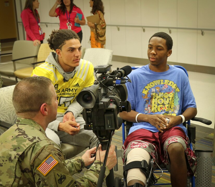 Army Reserve Staff Sgt. Steve Engle, a broadcast journalist with the 367th Mobile Public Affairs Detachment, 318th Press Camp Headquarters, interviews 15-year-old Jalen Williams (right), one of the children in the Children's Health Department of the University Hospital in San Antonio Jan. 3, as Jaelan Phillips (left) a high-school student and defensive end for the west team of the U.S. Army All-American Bowl looks on.  More than 30 high-school athletes participating in the upcoming Army All-American Bowl and their Soldier mentors took the opportunity to visit with kids at the hospital as part of a community relations event.  For 16 years the Army All-American Bowl has been the nation's premier high school football game, serving as the preeminent launching pad for America's future college and National Football League stars. (Official U.S. Army Reserve Photo by Sgt. 1st Class Brent C. Powell)