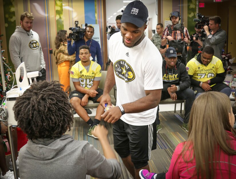 Cam Akers, a running back from Clinton, Mississippi, who will represent the east team in the Army All-American Bowl on Jan. 7, gives a fist bump to Brian McGraw, one of the children in the Children's Heath Department of the University Hospital in San Antonio.  More than 30 athletes and their Soldier mentors took the opportunity to visit with kids at the hospital as part of a community relations event Jan. 3.  For 16 years the Army All-American Bowl has been the nation's premier high school football game, serving as the preeminent launching pad for America's future college and National Football League stars. (Official U.S. Army Reserve Photo by Sgt. 1st Class Brent C. Powell)