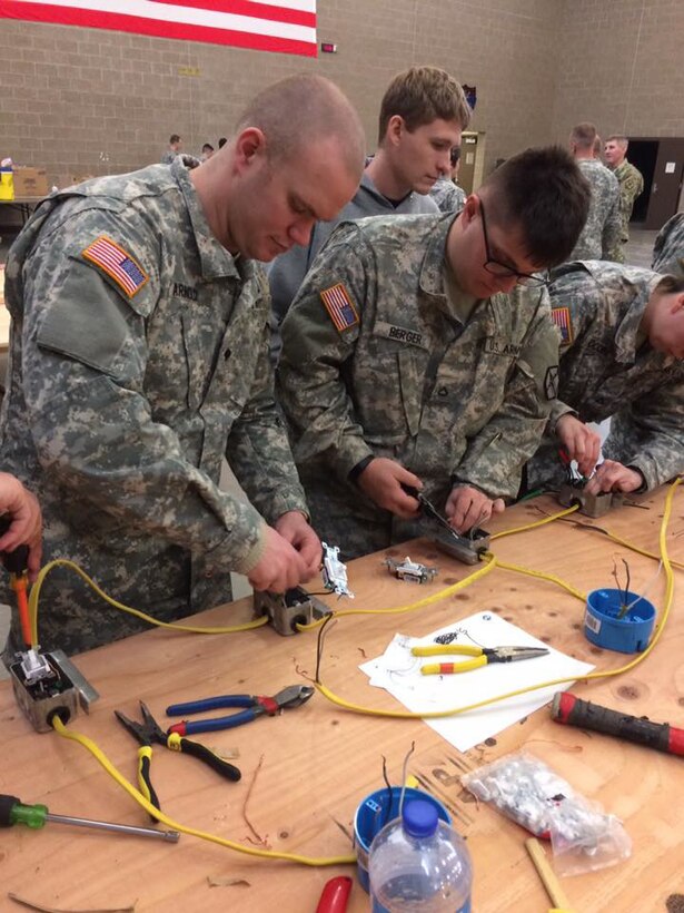 Spc. Johnathan A. Arnold, left, and Pfc. Dylan B. Berger wire a three-way switch that controls two lightbulbs at the 672nd Engineer Company vertical engineer skills competition held Dec. 10 in Missoula, Mont. The vertical engineer skills competition was held to inspire the same enthusiasm for vertical engineers that is held in other areas of the Corps of Engineers, and to show off Army Reserve life to members of the community (U.S. Army Reserve Photo by Sgt. 1st Class Leroy E. Bierfreund/Released).