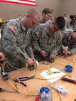 Spc. Johnathan A. Arnold, left, and Pfc. Dylan B. Berger wire a three-way switch that controls two lightbulbs at the 672nd Engineer Company vertical engineer skills competition held Dec. 10 in Missoula, Mont. The vertical engineer skills competition was held to inspire the same enthusiasm for vertical engineers that is held in other areas of the Corps of Engineers, and to show off Army Reserve life to members of the community (U.S. Army Reserve Photo by Sgt. 1st Class Leroy E. Bierfreund/Released).