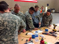 Pfc. Hayley R. Goodin, an indoor electrician, right, shows Pfc. Dylan B. Berger, a carpentry and masonry specialist, a useful technique for setting up an electrical box while a civilian watches earnestly at the 672nd Engineer Company vertical engineer skills competition held Dec. 10 in Missoula, Mont. The vertical engineer skills competition was held to inspire the same enthusiasm for vertical engineers that is held in other areas of the Corps of Engineers, and to show off Army Reserve life to members of the community (U.S. Army Reserve Photo by Sgt. 1st Class Leroy E. Bierfreund/Released).