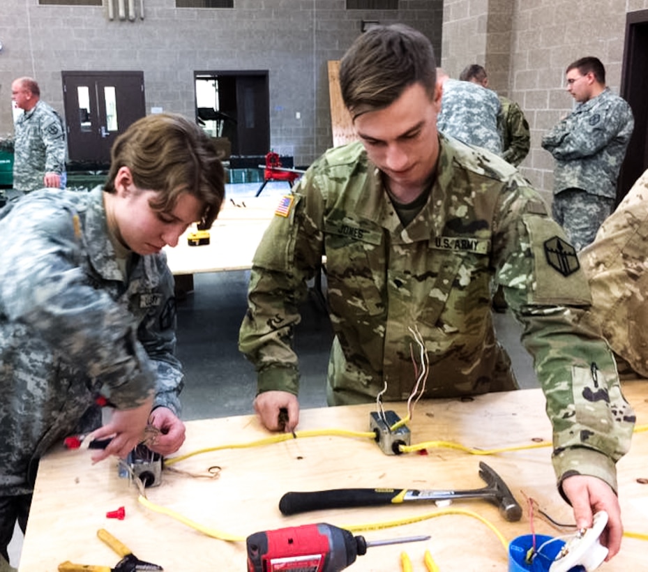 Pfc. Gabrielle F. Coppedge, left, and Spc. Steph Jones, right, work together to wire a three-way switch that controls a lighting system at the 672nd Engineer Company vertical engineer skills competition held Dec. 10 in Missoula, Mont. The vertical engineer skills competition was held to inspire the same enthusiasm for vertical engineers that is held in other areas of the Corps of Engineers, and to show off Army Reserve life to members of the community (U.S. Army Reserve Photo by Sgt. 1st Class Leroy E. Bierfreund/Released).