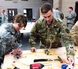 Pfc. Gabrielle F. Coppedge, left, and Spc. Steph Jones, right, work together to wire a three-way switch that controls a lighting system at the 672nd Engineer Company vertical engineer skills competition held Dec. 10 in Missoula, Mont. The vertical engineer skills competition was held to inspire the same enthusiasm for vertical engineers that is held in other areas of the Corps of Engineers, and to show off Army Reserve life to members of the community (U.S. Army Reserve Photo by Sgt. 1st Class Leroy E. Bierfreund/Released).