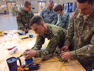 Sgt. Justin C. Payzant and Spc. Steph Jones put the finishing touches on wiring for a light and single pole switch at the 672nd Engineer Company vertical engineer skills competition held Dec. 10 in Missoula, Mont. The vertical engineer skills competition was held to inspire the same enthusiasm for vertical engineers that is held in other areas of the Corps of Engineers, and to show off Army Reserve life to members of the community (U.S. Army Reserve Photo by Sgt. 1st Class Leroy E. Bierfreund/Released).