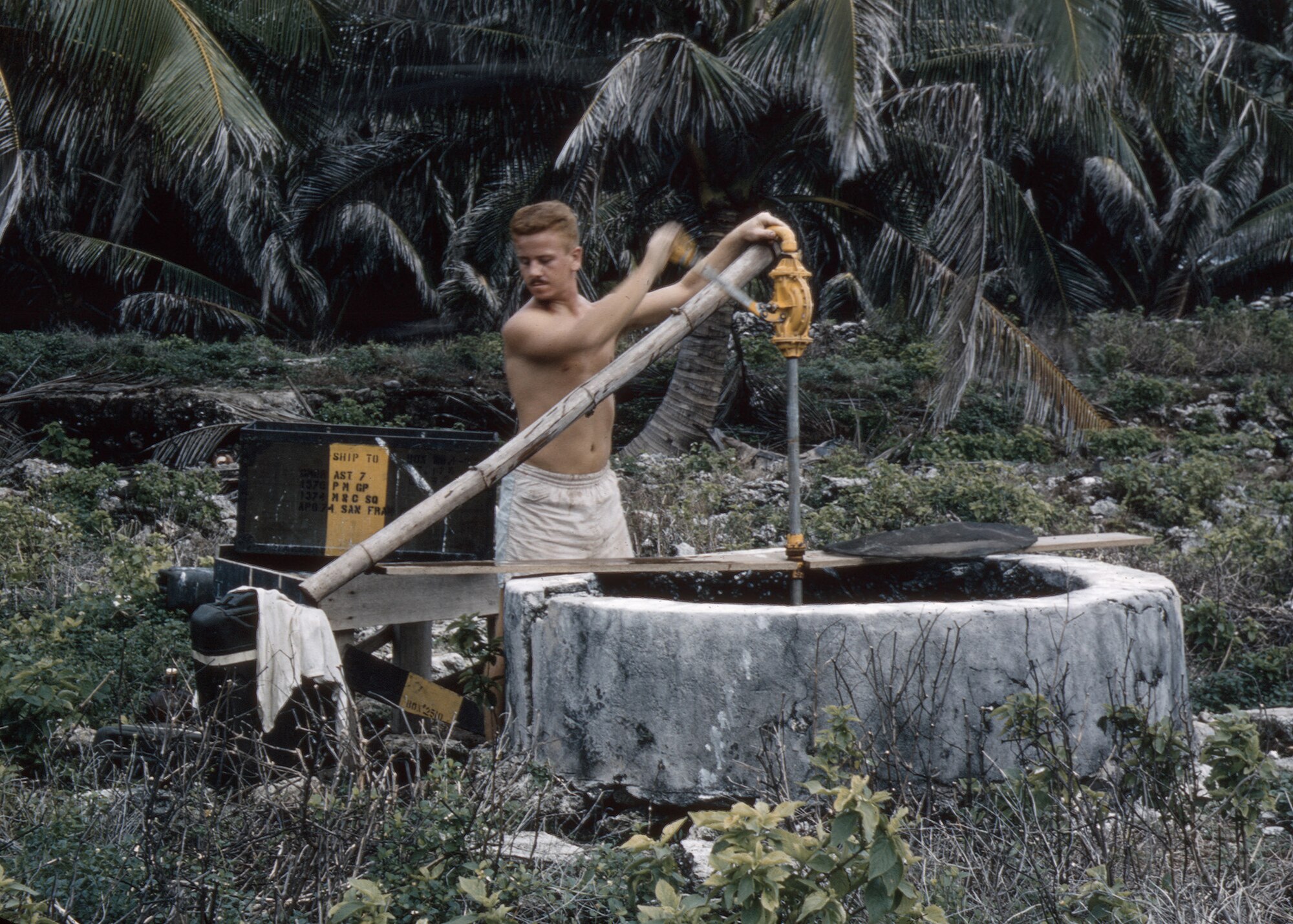 Airman 2nd Class Bob ‘Red’ Cunningham, 1374th Mapping and Charting Squadron, pumps water from an old well on North Danger Island in 1956. The Airmen only used this for laundry and washing. Drinking water was delivered in 55-gallon barrels. (Courtesy photo/Bob Cunningham)