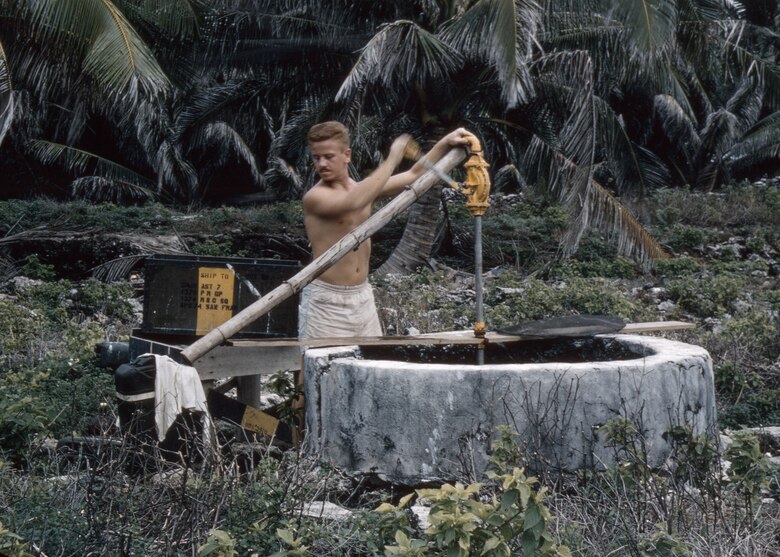 Airman 2nd Class Bob â€˜Redâ€™ Cunningham, 1374th Mapping and Charting Squadron, pumps water from an old well on North Danger Island in 1956. The Airmen only used this for laundry and washing. Drinking water was delivered in 55-gallon barrels. (Courtesy photo/Bob Cunningham)