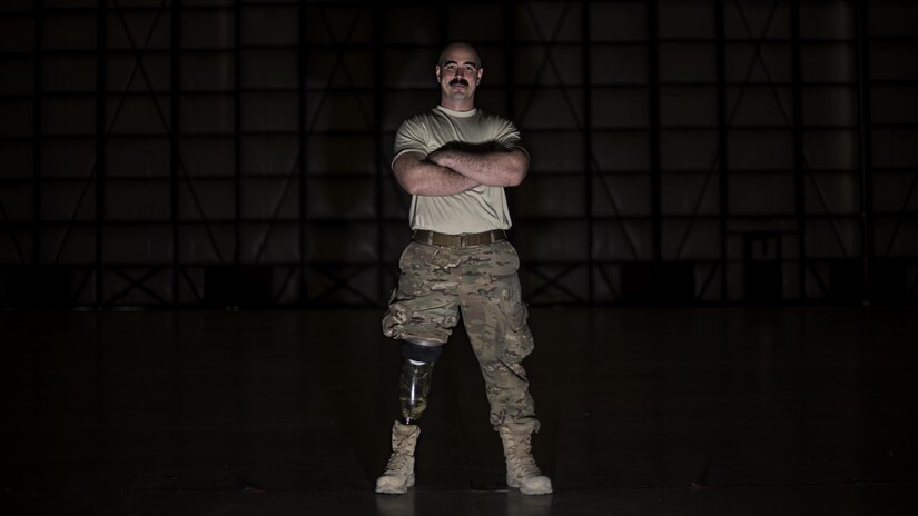 Tech. Sgt. Jason Caswell, 455th Expeditionary Aircraft Maintenance Squadron C-130 Hercules debrief NCO-in-charge, stands in a C-130 hangar at Bagram Airfield, Afghanistan, Jan. 5, 2017. After a sports injury in 2010, Caswell underwent a year of surgeries, two years of painful limb-recovery therapy, followed by physical therapy. In October 2014, his limb still hadn’t healed and began to worsen. Caswell elected to amputate his injured leg. (U.S. Air Force photo by Staff Sgt. Katherine Spessa)