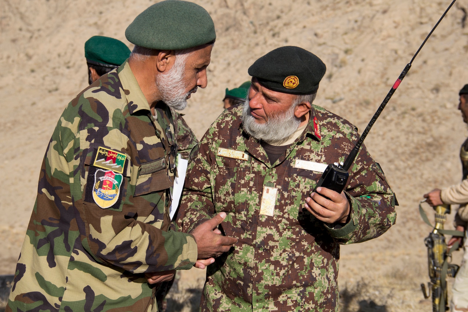 Two Afghan National Army officers with the 201st Corps discuss call for fire missions during a tolay attack battle drill near Camp Torah, Afghanistan, Dec. 27, 2016. The attack battle drill was conducted as part of the corps collective training cycle to build capability and capacity within the organization. (U.S. Army photo by Capt. Grace Geiger)