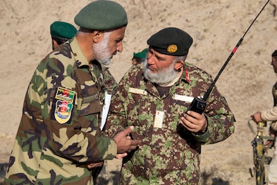 Two Afghan National Army officers with the 201st Corps discuss call for fire missions during a tolay attack battle drill near Camp Torah, Afghanistan, Dec. 27, 2016. The attack battle drill was conducted as part of the corps collective training cycle to build capability and capacity within the organization. (U.S. Army photo by Capt. Grace Geiger)