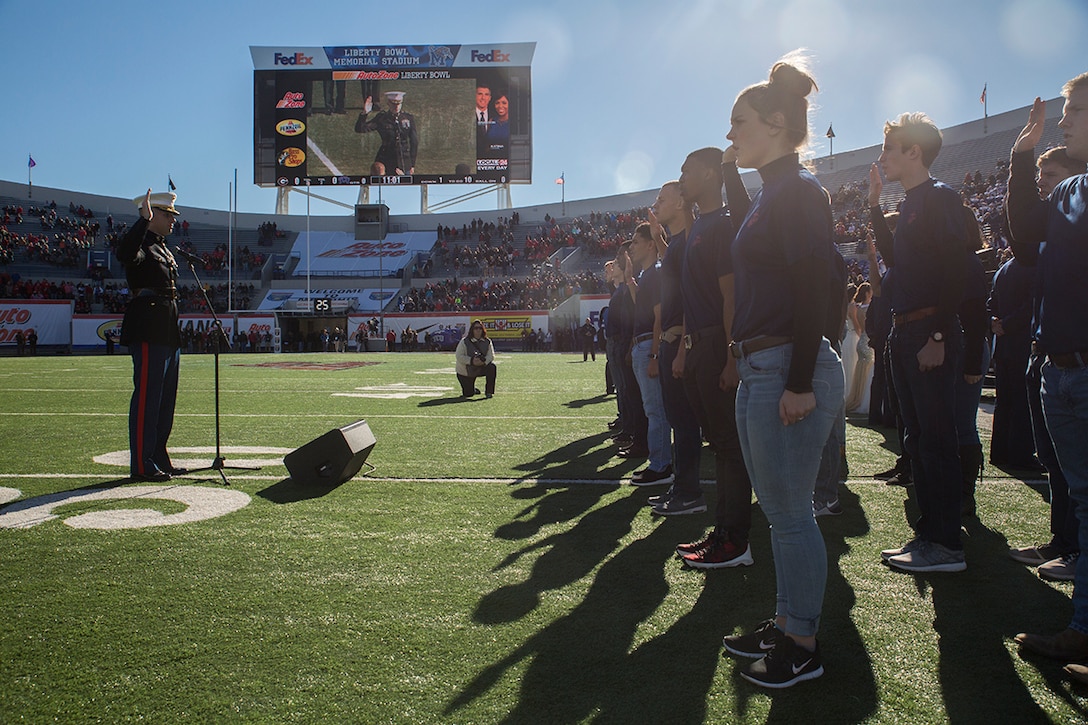 Major Jonathan Landers, commanding officer for Recruiting Station Nashville, has his right hand raised as the poolees repeat the Oath of Enlistment before the Autozone Liberty Bowl Dec. 30, 2016. (Photo by Cpl. John-Paul Imbody)