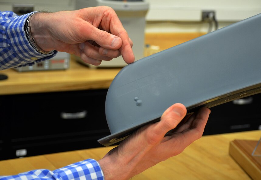 Dr. Dan Berrigan points to an embedded antenna on an MQ-9 aircraft part made possible through functional applications of additive manufacturing.  Flexible circuits, embedded antennas and sensors are just a few of the potential manufacturing capabilities his team is exploring using additive technology. (U.S. Air Force photo/Marisa Alia-Novobilski)