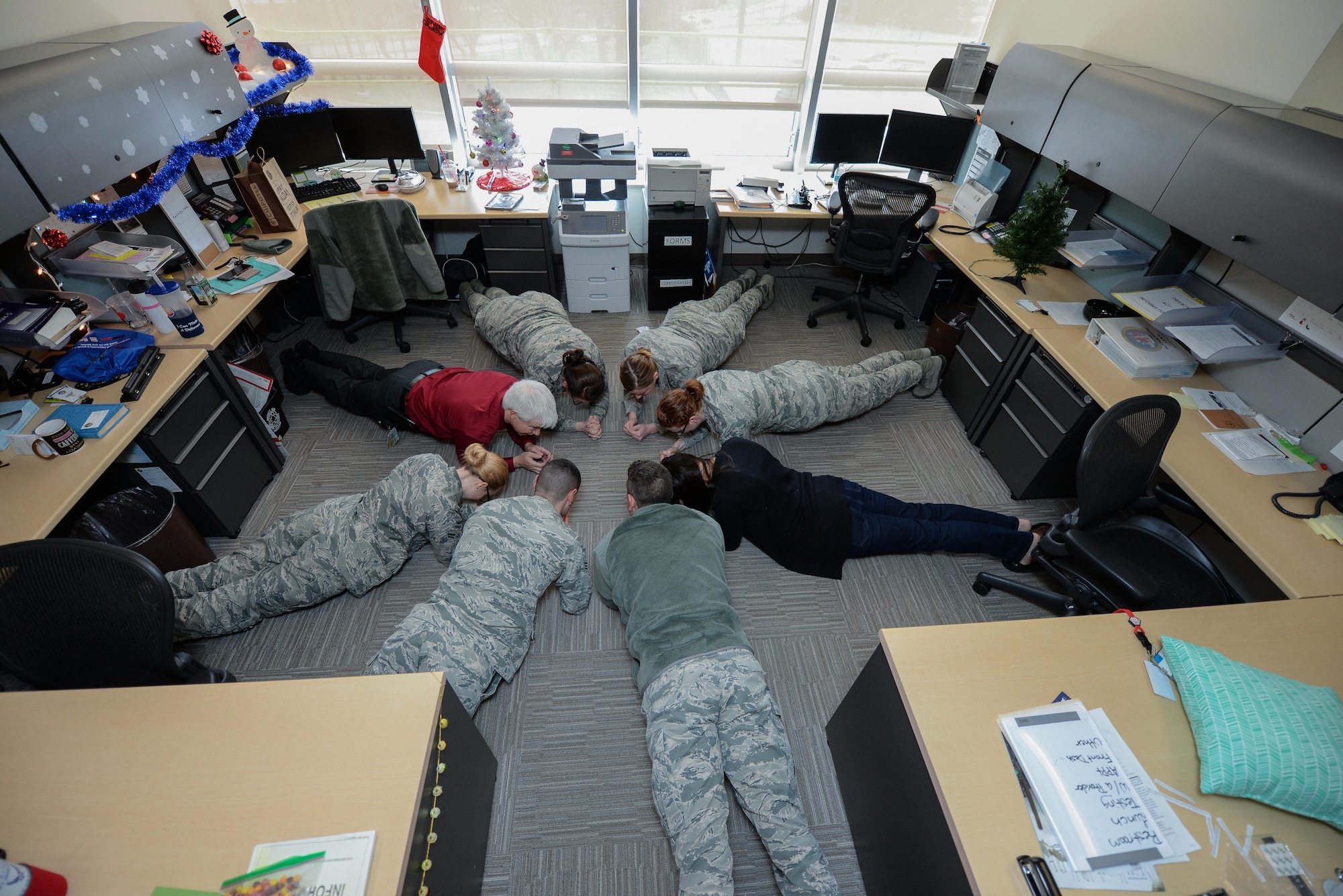 Members of the 55th Medical Group mental health section, perform planks during the work day at Offutt Air Force Base, Nebraska, Dec. 23, 2016 in the base clinic as a strategy to promote a culture of fitness in Airmen’s daily lives. Members perform small exercises throughout the day instead of one intense workout to keep the body more active and healthy. (U.S. Air Force photo by Zachary Hada)
