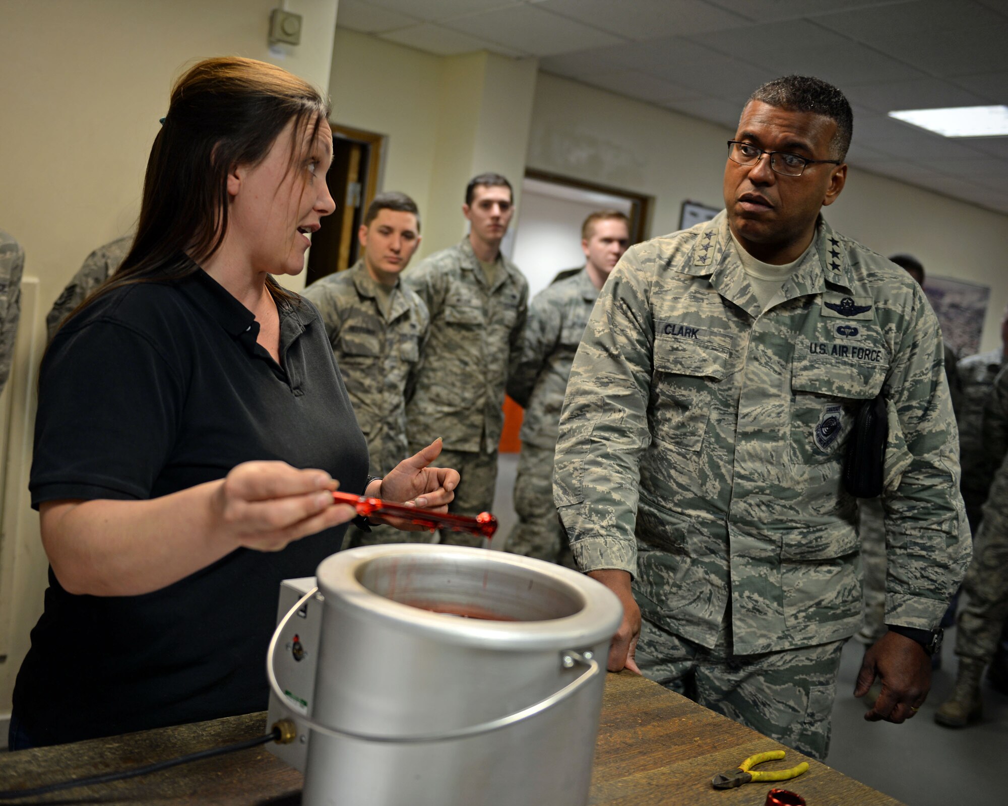 Mia Tobitt, 100th Maintenance Squadron isochronal inspection support section chief, demonstrates and explains a tool dipping innovation the 100th MXS implemented to U.S. Air Force Lt. Gen. Richard Clark, right, 3rd Air Force commander, during his visit Jan. 5, 2016, on RAF Mildenhall, England. Tools are dipped in a special, reusable plastic to prevent corrosion. This innovation saves 653 man hours and $35,000, a year. (U.S. Air Force photo by Senior Airman Christine Halan)