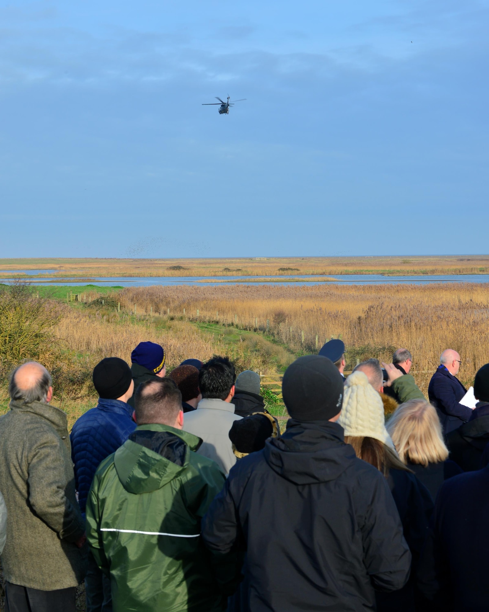 Family, friends, U.S. Airmen and U.K. community members gather at Cley-Next-the-Sea to watch an HH-60G Pave Hawk flyover during a memorial ceremony Jan. 6, 2017. A memorial stone was dedicated to the four aircrew members who made the ultimate sacrifice during a low-level training mission on Jan. 7, 2014. (U.S. Air Force photo by Staff Sgt. Stephanie Longoria)