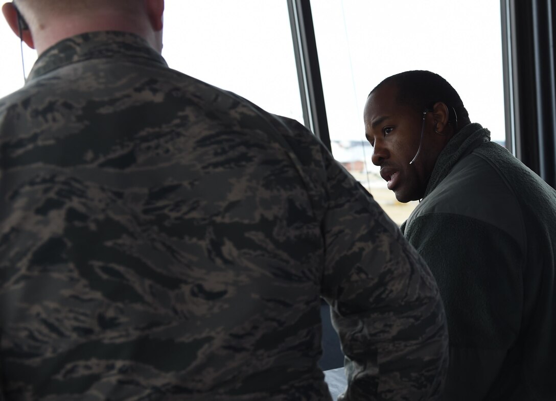 U.S. Air Force Senior Airman Chino Ross, right, 1st Operations Support Squadron air traffic controller, trains Senior Airman Patrick Taylor, 1st OSS air traffic controller, on air traffic control tower practices at Joint Base Langley-Eustis, Va., Dec. 16, 2016. Patrick recently completed upgrade training to assist tower operations. (U.S. Air Force photo by Staff Sgt. Natasha Stannard)