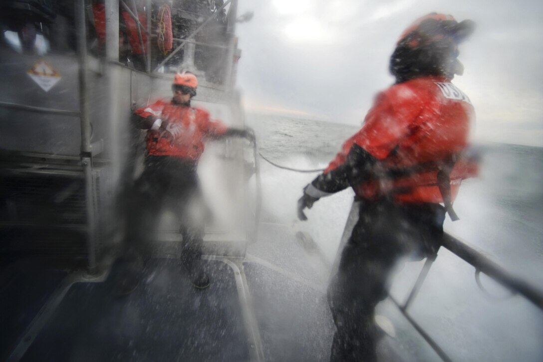 Coast Guardsmen brace themselves as heavy waves wash against a cutter during training in the waters near Coast Guard Station Shinnecock in Hampton Bays, N.Y., Dec. 22, 2016. Air National Guard photo by Staff Sgt. Christopher S. Muncy