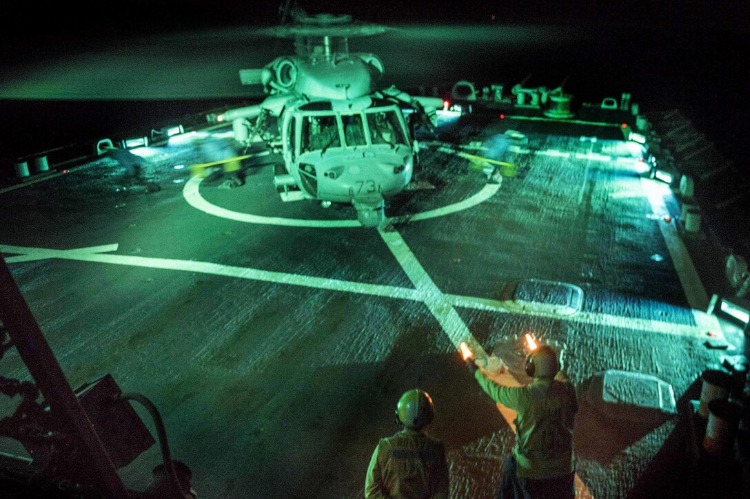 Navy Petty Officer 2nd Class Jarret Hal signals as crew members remove chocks and chains from a MH-60S Knighthawk helicopter as it prepares to lift off the flight deck of the USS Mahan in the Arabian Sea, Jan. 3, 2015. Hal is a boatswain's mate and the Knighthawk is assigned to Helicopter Sea Combat Squadron 26. The guided-missile destroyer is deployed in the U.S. 5th Fleet area of operations to support maritime security operations and theater security operation efforts. Navy photo by Petty Officer 1st Class Tim Comerford