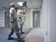 Tech. Sgt. Bill Beddow, 919th Special Operations Maintenance Squadron, and Senior Airman Martin Sturgeon, 556th Red Horse Squadron, apply texturing to the sheetrock walls of the newly opened Commando Closet Dec. 14 at Duke Field, Fla.  The volunteer effort culminated in the grand opening of the Closet Jan. 7, where Airmen can come in and get donated uniforms, boots, etc.  (U.S. Air Force photo/Dan Neely)