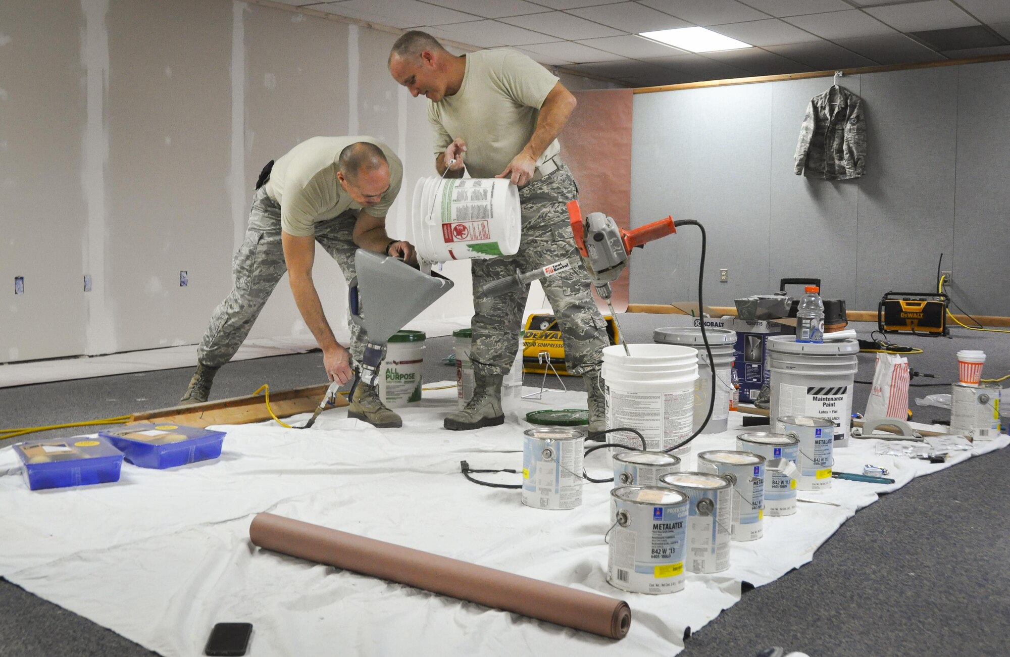Senior Airman Martin Sturgeon, 556th Red Horse Squadron, and Tech. Sgt. Bill Beddow, 919th Special Operations Maintenance Squadron, refill texturing solution prior to covering the sheetrock of the newly opened Commando Closet Dec. 14 at Duke Field, Fla.  The volunteer effort culminated in the grand opening of the Closet Jan. 7, where Airmen can come in and get donated uniforms, boots, etc.  (U.S. Air Force photo/Dan Neely)
