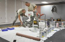 Senior Airman Martin Sturgeon, 556th Red Horse Squadron, and Tech. Sgt. Bill Beddow, 919th Special Operations Maintenance Squadron, refill texturing solution prior to covering the sheetrock of the newly opened Commando Closet Dec. 14 at Duke Field, Fla.  The volunteer effort culminated in the grand opening of the Closet Jan. 7, where Airmen can come in and get donated uniforms, boots, etc.  (U.S. Air Force photo/Dan Neely)