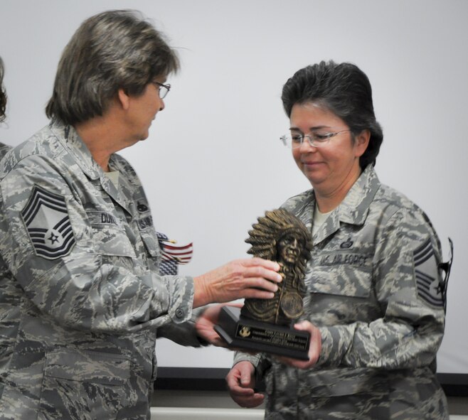 Chief Master Sgt. Pamela Duvall, 919th Special Operations Maintenance Group, presents a Native American chief bust to newly promoted Chief Master Sgt. Laurie Kent, 919th Special Operations Force Support Squadron, at her Chief Induction ceremony Jan. 7 at Duke Field, Fla.  Kent was promoted to chief via the Stripes for Exceptional Performers II program in August.  (U.S. Air Force photo/Lt. Col. James Wilson)