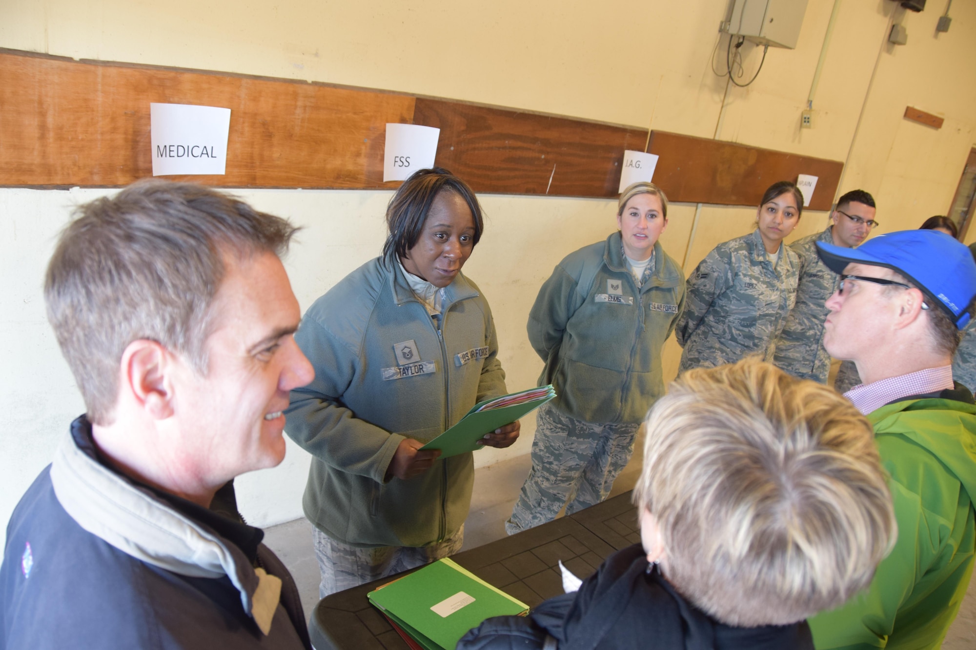 Master Sgt. Paula Taylor, 433rd Logistics and Readiness Squadron plans and logistics section NCO in charge,  Staff Sgt. Catharine Elms, 433rd Force Support Squadron, chief of personnel readiness, and Airman 1st Class Irmalinda Lopez, 433rd FSS force management technician, assist Honorary Commanders go through a mock deployment line Jan. 7, 2017 at Joint Base San Antonio-Lackland, Texas. The demonstration, which also included donning chemical warfare protection suits, was part of the 433rd Airlift Wing Honorary Commanders program tour of the 433rd Mission Support Group. (U.S. Air Force photo/Tech. Sgt. Carlos J. Trevino)