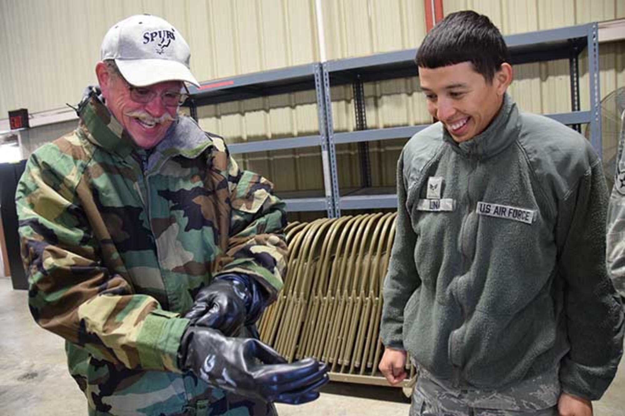 Steve Richmond, an alumni of the Honorary Commander’s program, adjusts the gloves of his chemical warfighter under the supervision of Senior Airman Michael Luna, transportation specialist with the 433rd Force Support Squadron during a mock deployment Jan. 7, 2017 at Joint Base San Antonio-Lackland, Texas.  The logistics readiness demonstration was a portion of the 433rd Airlift Wing Honorary Commanders program tour of the 433rd Mission Support Group. (U.S. Air Force photo/Tech. Sgt. Carlos J. Trevino)