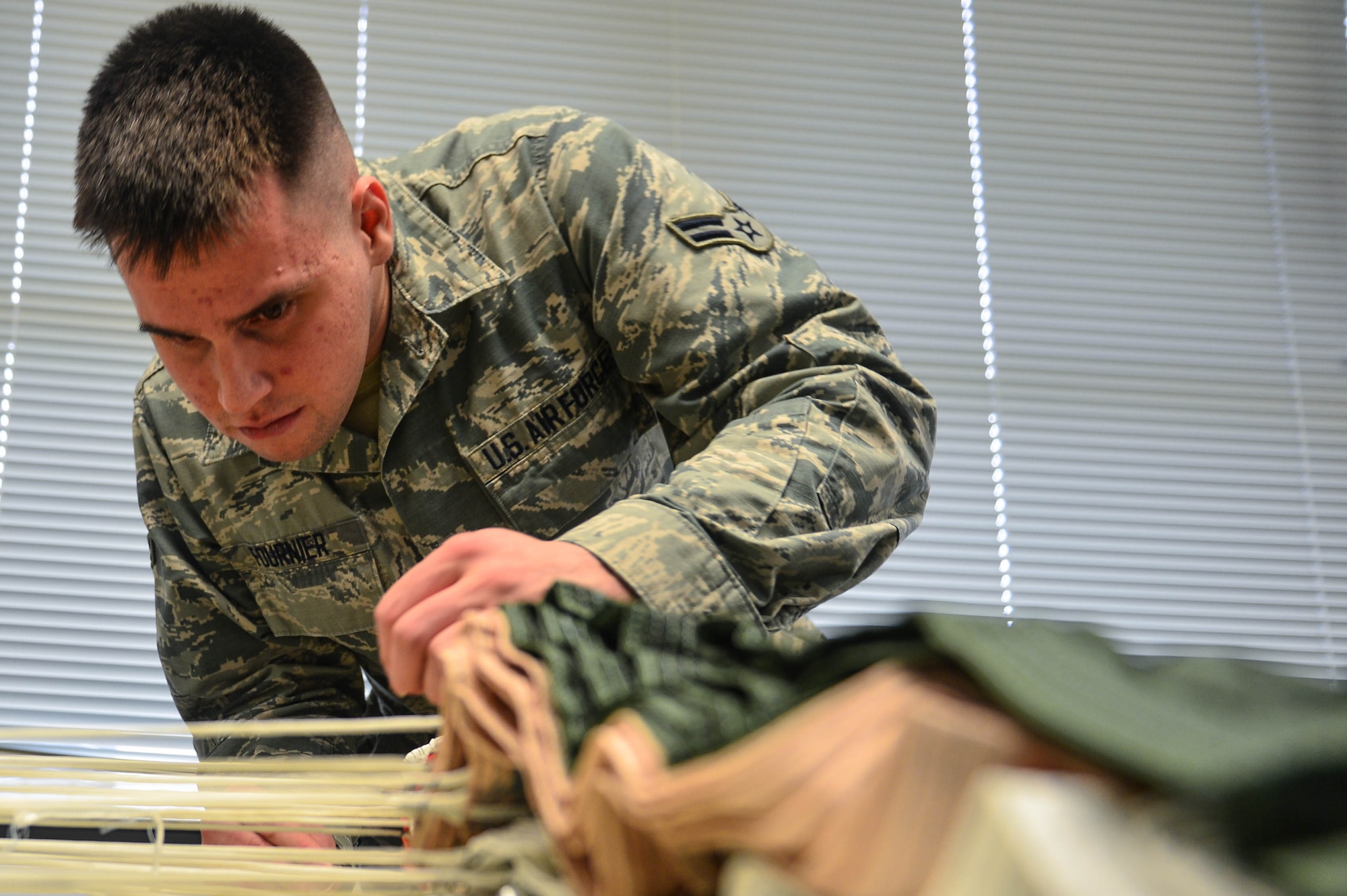 U.S. Air Force Airman 1st Class Nicholas Fournier, 20th Operations Support Squadron aircrew flight equipment journeyman, checks parachute suspension lines for container fragments at Shaw Air Force Base, S.C., Jan. 4, 2017. AFE Airmen must thoroughly inspect the lines for tears and debris to ensure proper discharge of the parachute in the event of an emergency. (U.S. Air Force photo by Airman 1st Class Christopher Maldonado)