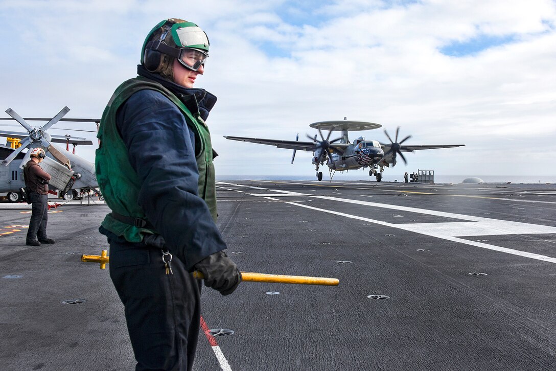 Navy Petty Officer 3rd Class Tyler Mabie stands by to guide an arresting cable as an E-2C Hawkeye makes the first arrested cable landing of the cruise on the flight deck of the aircraft carrier USS Carl Vinson in the Pacific Ocean, Jan. 5, 2017. Mabie is an aviation boatswain’s mate, equipment. Navy photo by Petty Officer 2nd Class Sean M. Castellano