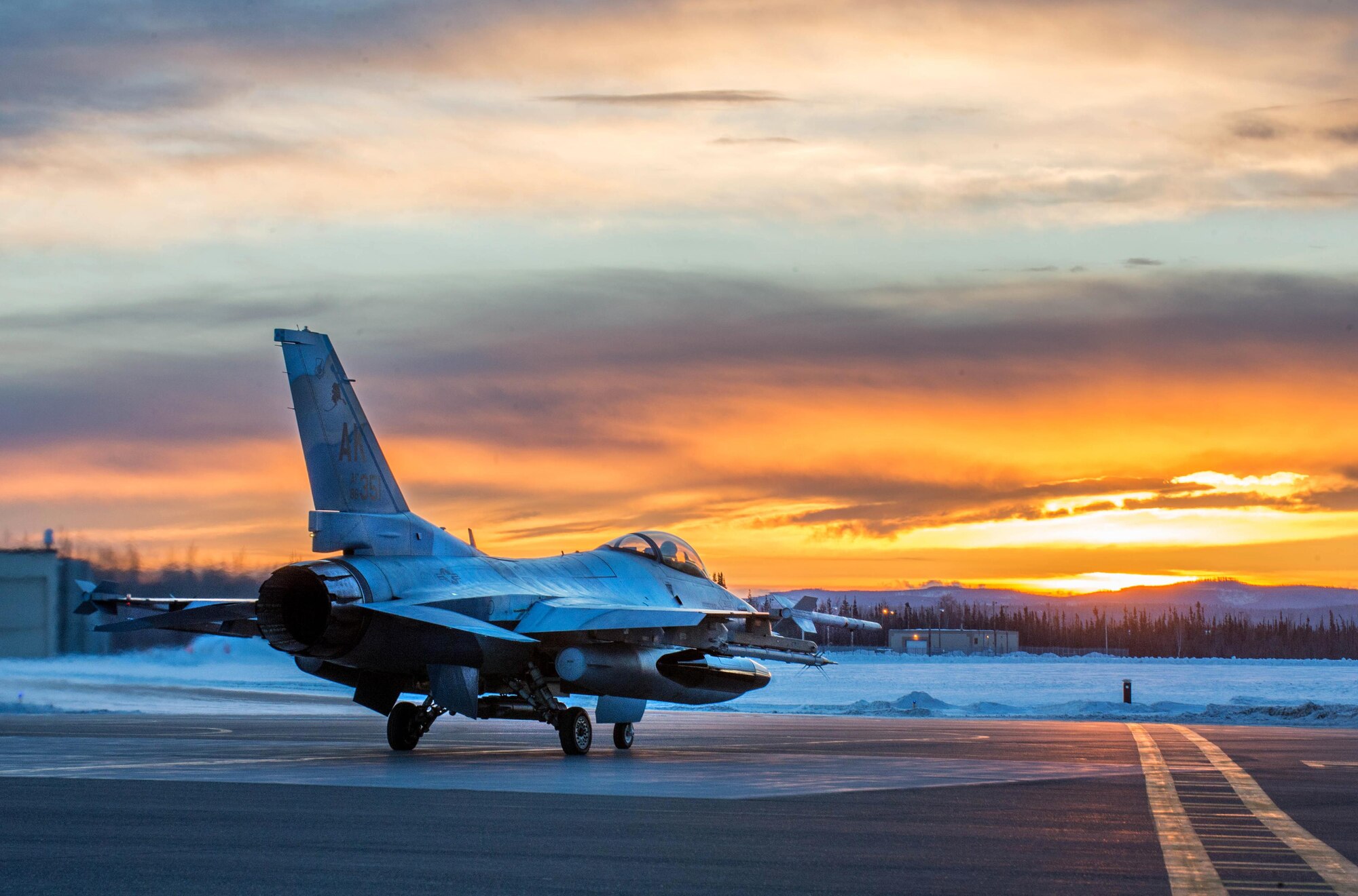 An F-16 Fighting Falcon with the 18th Aggressor Squadron prepares to take off from Eielson Air Force Base, Alaska, shortly after sunrise Jan. 24, 2016, in transit to Kadena Air Base, Japan, to participate in training exercises. More than 150 maintainers from the 354th Fighter Wing will keep the aggressors in the air and prepare Airmen, Sailors and Marines for contingency operations along with coalition partners in the Pacific theater. (U.S. Air Force photo/Staff Sgt. Shawn Nickel)