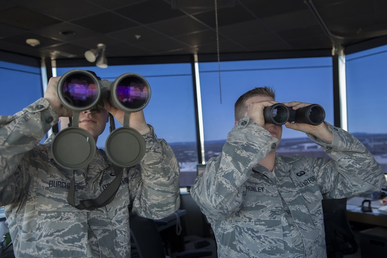 Airman 1st Class Brandon Burchell and Senior Airman Jakob Hunley, both 7th Operations Support Squadron air traffic controllers, scan the airfield using binoculars Jan. 25, 2016, at Dyess Air Force Base, Texas. Air traffic controllers scan the flightline to check for wildlife, watch for potential vehicular traffic interfering with air operations and to ensure the aircrafts’ landing gear are down as they land. (U.S. Air Force photo/Airman 1st Class Austin Mayfield)