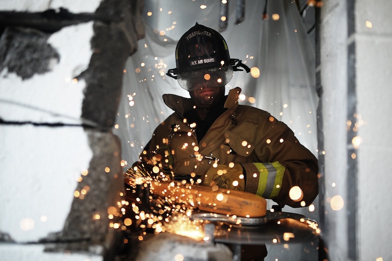 Staff Sgt. Daniel Glenn, a firefighter with the 106th Rescue Wing, operates a powered saw to cut through a reinforced cinder block wall at Francis S. Gabreski Air National Guard Base, N.Y., Aug. 25, 2016. (U.S. Air National Guard photo/Staff Sgt. Christopher S. Muncy)