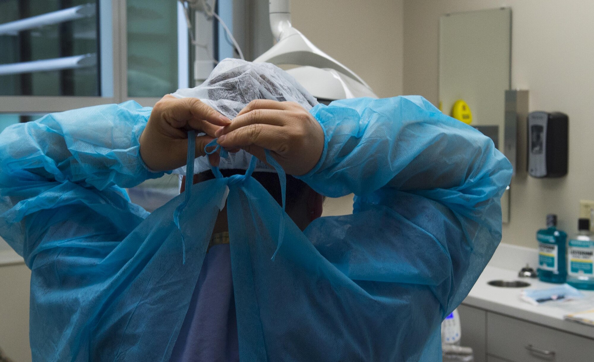 Master Sgt. Millicent Cavazos, 779th Medical Group dental squadron dental hygienist, ties a surgical gown before performing a dental cleaning at Joint Base Andrews, Md., Jan. 6, 2017. The clinic, based out of the new edition to Malcolm Grow Medical Clinics and Surgery Center, sees approximately 500 patients a month. (U.S. Air Force photo by Senior Airman Mariah Haddenham)
