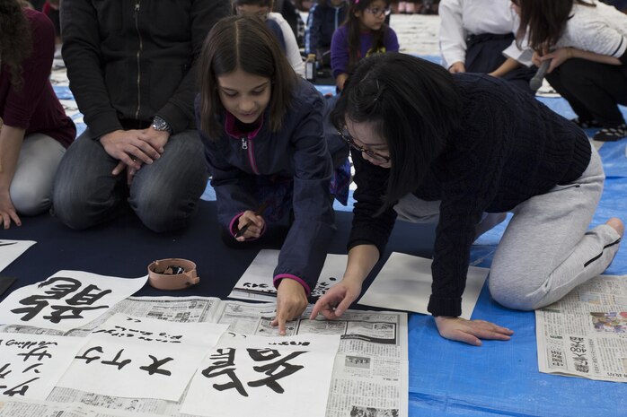 Yamamoto Yuko, a local calligraphy instructor, helps a child from Marine Corps Air Station Iwakuni practice calligraphy during a calligraphy event in Waki Town, Japan, Jan. 7, 2017. The children learned how to write their goals in Kanji for the new year. Similar to the American tradition of New Year’s resolutions, the Japanese use calligraphy to write their goals at the beginning of every new year.   (U.S. Marine Corps photo by Lance Cpl. Joseph Abrego)