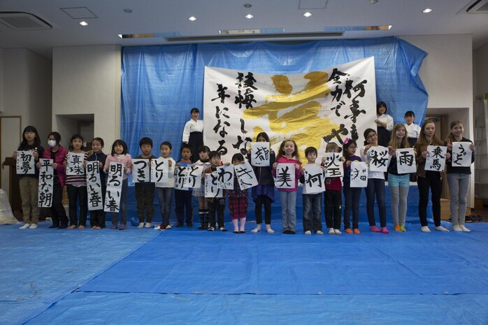Children from Marine Corps Air Station Iwakuni and Japanese local children pose for a photo with their completed art work during a calligraphy event in Waki Town, Japan, Jan. 7, 2017. The children learned how to write their goals in Kanji for the new year. Similar to the American tradition of New Year’s resolutions, the Japanese use calligraphy to write their goals at the beginning of every new year.   (U.S. Marine Corps photo by Lance Cpl. Joseph Abrego)