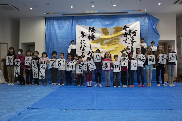 Children from Marine Corps Air Station Iwakuni and Japanese local children pose for a photo with their completed art work during a calligraphy event in Waki Town, Japan, Jan. 7, 2017. The children learned how to write their goals in Kanji for the new year. Similar to the American tradition of New Year’s resolutions, the Japanese use calligraphy to write their goals at the beginning of every new year.   (U.S. Marine Corps photo by Lance Cpl. Joseph Abrego)