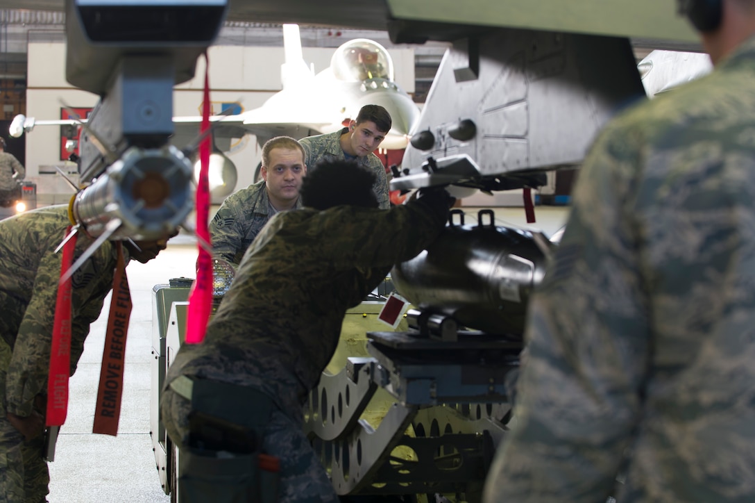 52nd Fighter Wing evaluators observe Staff Sgt. DeAnte Miller and Senior Airman Michael Curtis, both 52nd Aircraft Maintenance Squadron tactical aircraft weapons systems specialists, during the 52nd FW Load Crew of the Quarter competition at Spangdahlem Air Base, Germany, Jan. 6, 2017. Family, friends and members of the Spangdahlem community attended the competition to see which of the two teams of three maintenance Airmen would move on to the annual load competition. (U.S. Air Force photo by Senior Airman Dawn M. Weber)